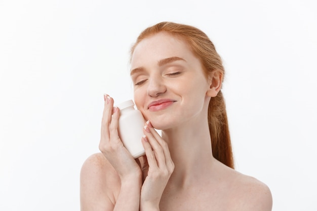 Bella ragazza sorridente che cattura farmaco, tenendo la bottiglia con le pillole.