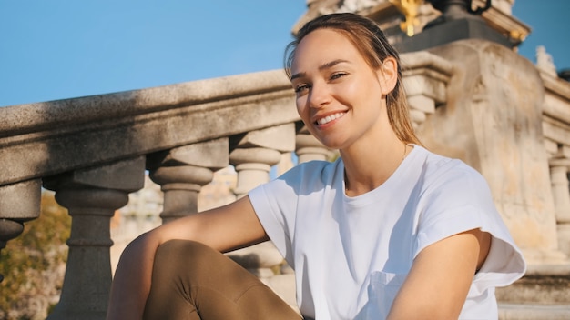 Beautiful smiling girl in white t-shirt sitting on old stairs