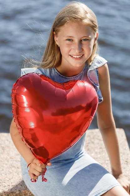 Bella ragazza sorridente con palloncino cuore