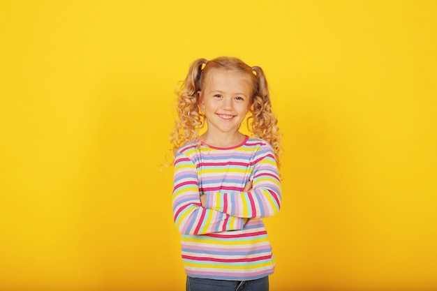 beautiful smiling happy blonde girl on a yellow background in a colored jacket