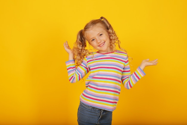 beautiful smiling happy blonde girl on a yellow background in a colored jacket