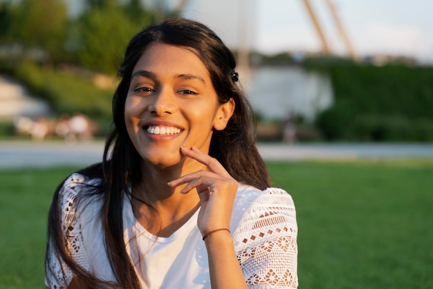 Beautiful smiling Indian woman looking at camera sitting in park, copy space. Natural beauty