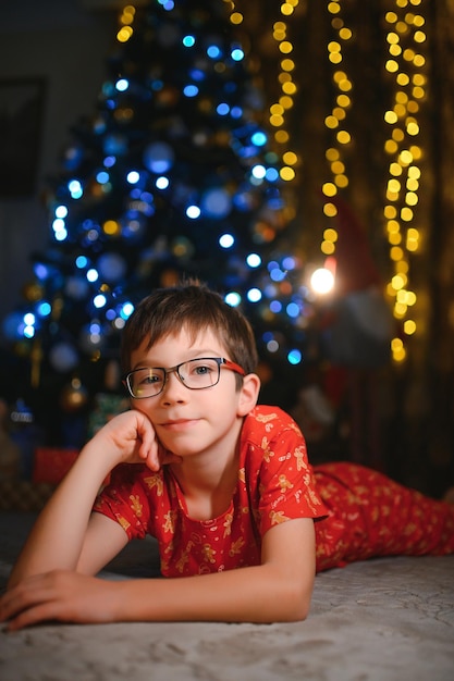 Beautiful smiling little boy near Christmas tree