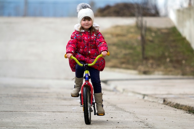 Beautiful smiling little girl riding bicycle in a park