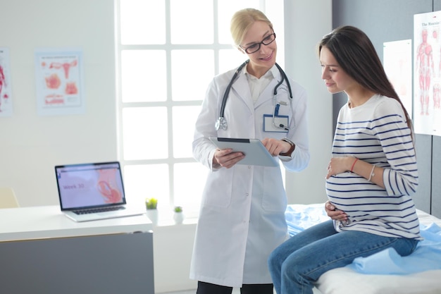 Beautiful smiling pregnant woman with the doctor at hospital