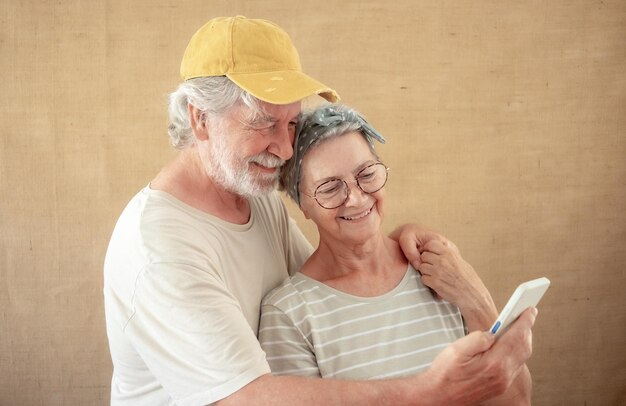 Beautiful smiling senior couple looking together at phone Bearded elderly man holding smartphone