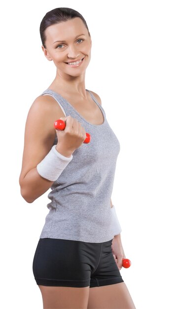 Beautiful smiling sporty female wearing sports clothes standing smiling looking at camera lifting weights isolated