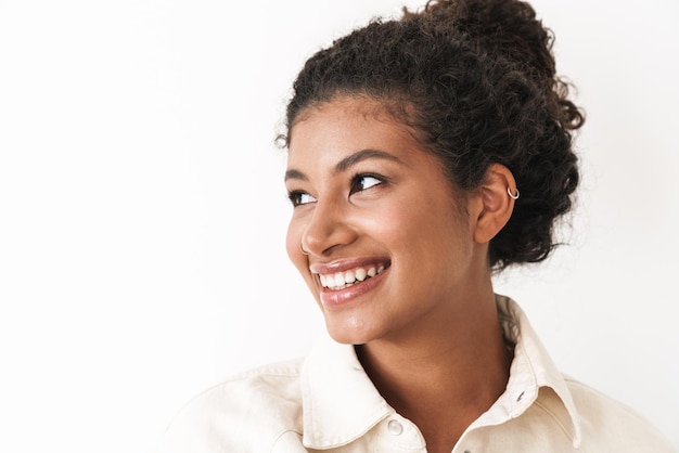 Beautiful smiling stylish young woman standing over white wall, posing