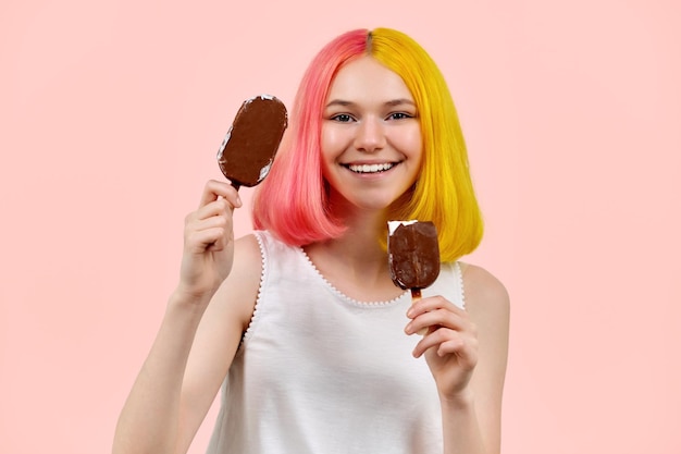 분홍색 배경에 맛있는 초콜릿 아이스크림을 얹은 아름다운 웃는 십대 소녀