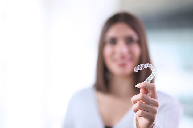 Beautiful smiling Turkish woman is holding an invisalign bracer includes copy space