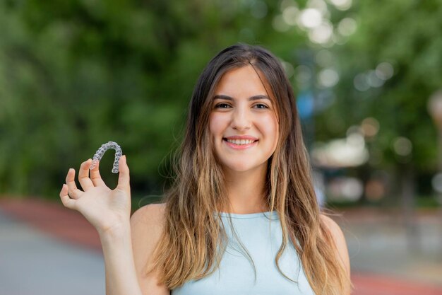 美しい笑顔のトルコの女性は、invisalignブレーサーを保持しています