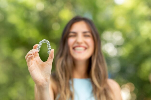 Photo beautiful smiling turkish woman is holding an invisalign bracer