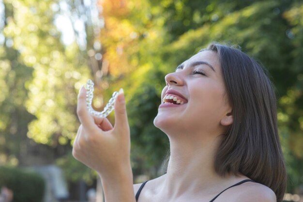 Beautiful smiling Turkish woman is holding an invisalign bracer