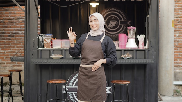 Beautiful smiling waitress ready to open cafe booth container