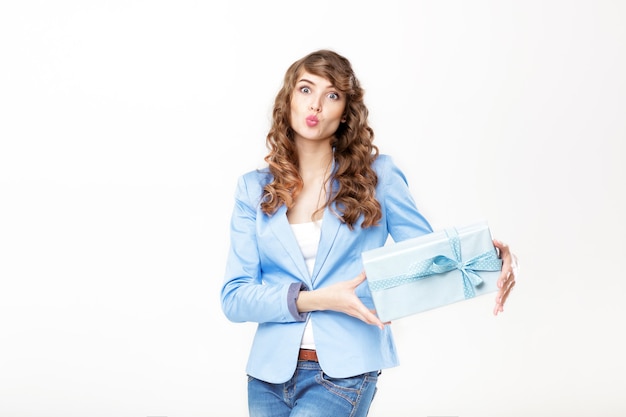 Beautiful smiling woman in blue jacket holds gift box with curly hair