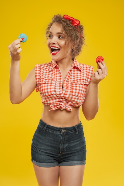 Beautiful smiling woman choosing between two macarons