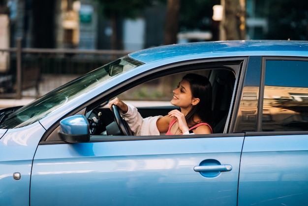 自動車に座っている車の女の子を運転する美しい笑顔の女性