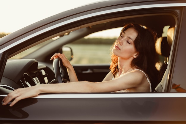 朝に車を運転する美しい笑顔の女性