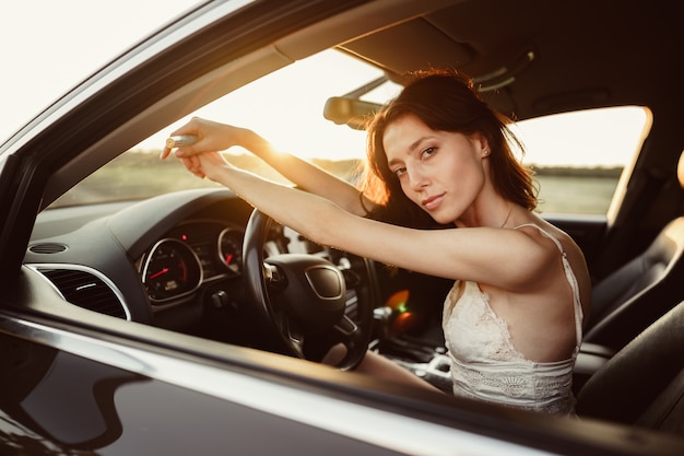 朝に車を運転する美しい笑顔の女性