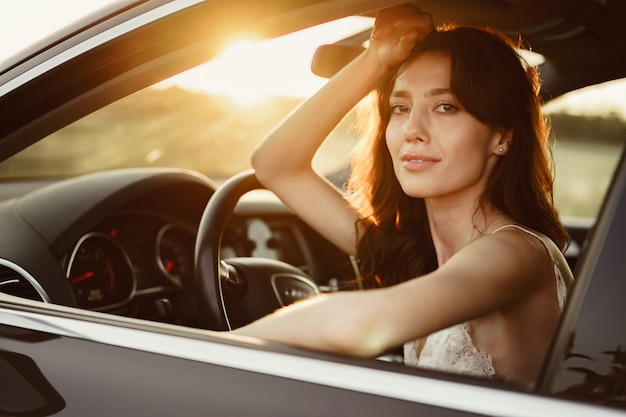 Красивая улыбающаяся женщина за рулем машины утром