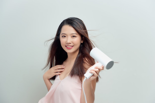 Beautiful smiling woman drying healthy long hair