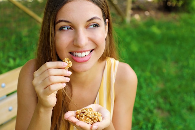 Beautiful smiling woman eating walnuts in the park