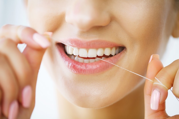 Photo beautiful smiling woman flossing healthy white teeth.