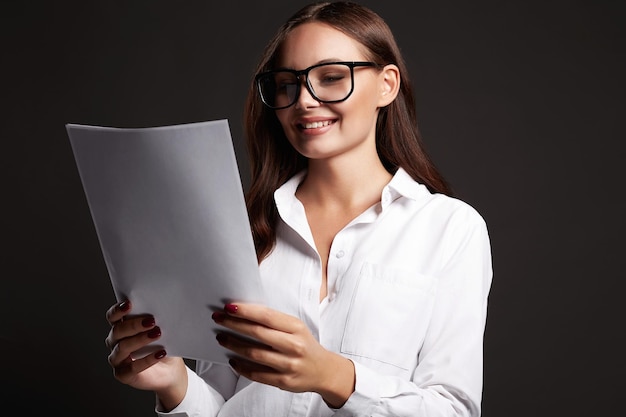 Beautiful smiling woman in glasses looking at documents