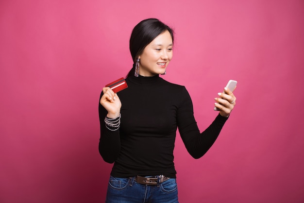 La bella donna sorridente sta esaminando il suo acquisto online del telefono che paga con la sua carta.