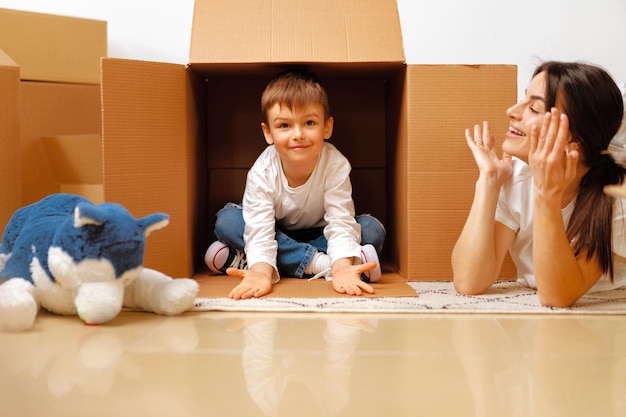 Beautiful smiling woman and little boy with cardboard boxes moving to new home