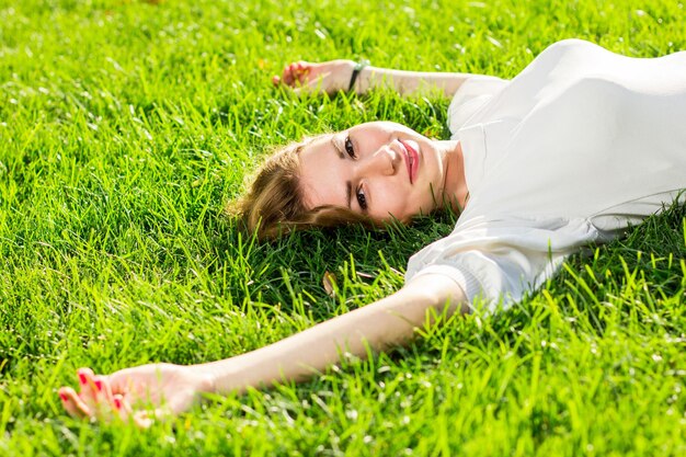 写真 屋外の芝生に横たわっている美しい笑顔の女性彼女は絶対に幸せです