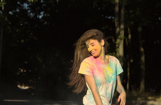 Beautiful smiling woman posing with Holi powder on her face and body