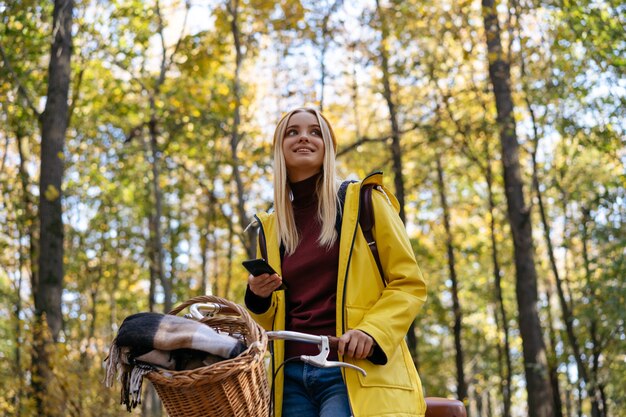 Beautiful smiling woman wearing yellow raincoat riding a bicycle in the forest Travel concept