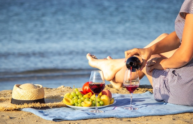 ビーチでワインを飲みながら美しい笑顔の女性。フルーツ赤ワイン。