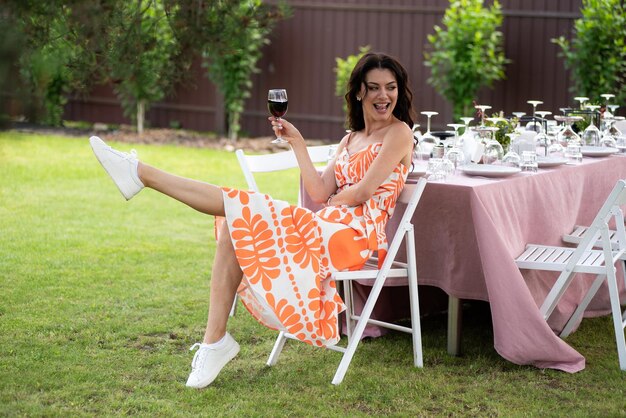 Beautiful smiling woman with glass of wine on summer background