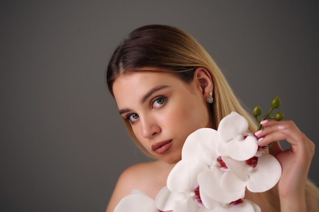 Beautiful smiling woman with orchid in studio.