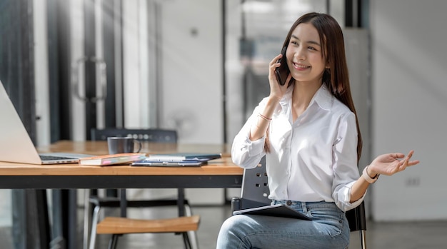 아름 다운 미소 젊은 아시아 사업가 직장에서 전화 통화