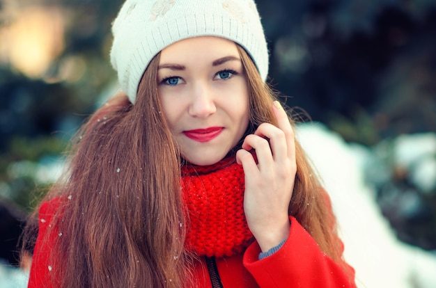 Beautiful smiling young girl in a red coat in winter.