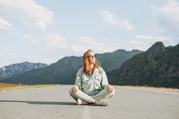 Beautiful smiling young woman traveler in casual clothes on road trip to the mountains Altai