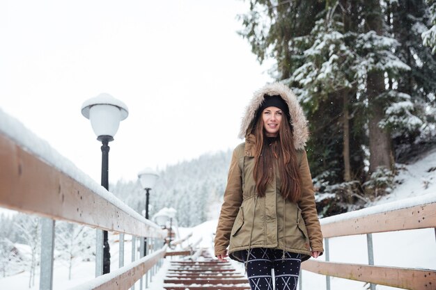 Beautiful smiling young woman walking on stairs in winter mountain resort