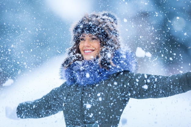 暖かい服を着て美しい笑顔の若い女性冬の雪の天気の肖像画の概念