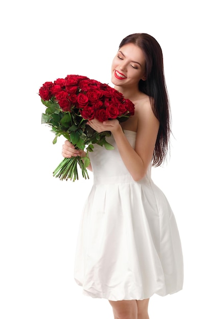 Beautiful smiling young woman in a white dress with a large bouquet of red roses on a white background. valentine's day