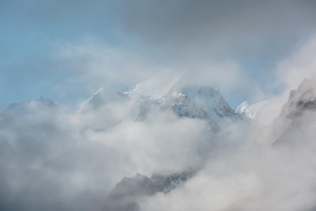 Beautiful snow castle in low clouds Lovely scenery with high snowy mountains in thick clouds Big air castles float in gantly cloudy sky Scenic view to large snow mountain in clearance of dense fog