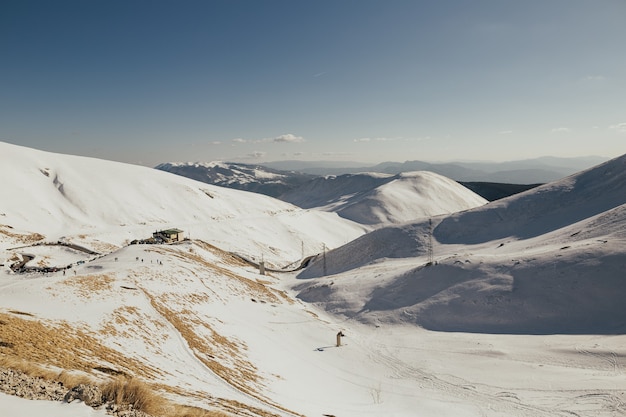 Beautiful snowy winter landscape panorama with ski resort, blue sky, ski tracks and skiers.