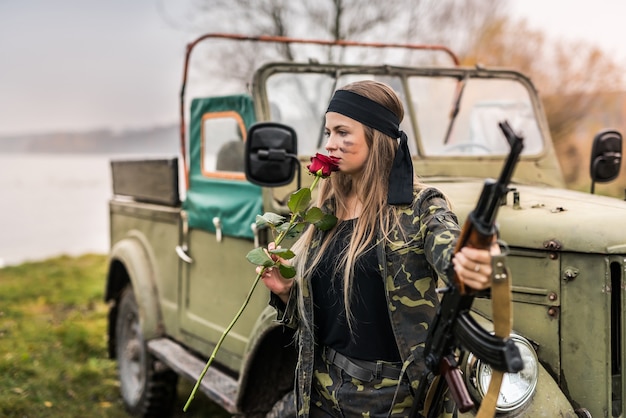 Beautiful soldier with rose flower and rifle