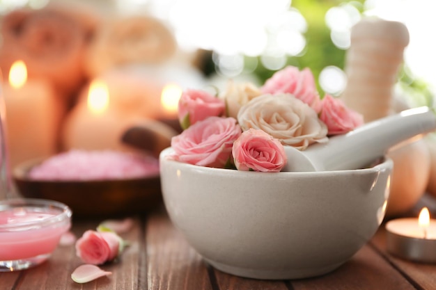 Красивая спа-композиция с цветами в миске на деревянном столе