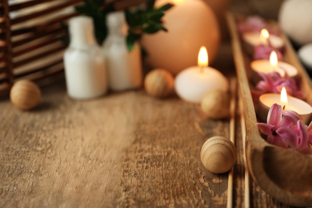 Beautiful spa composition with flowers and candles on wooden table