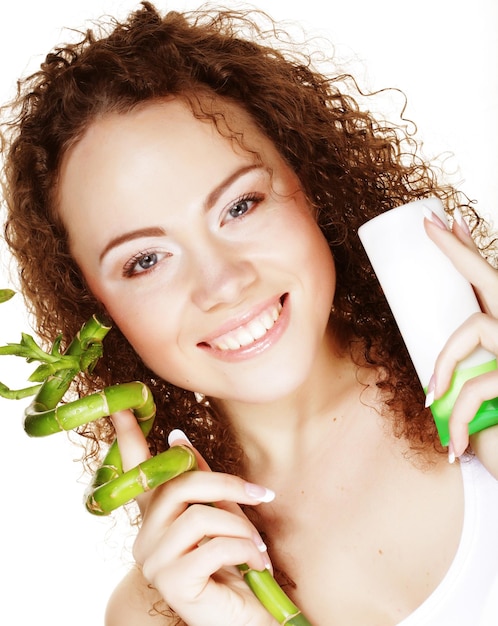 Beautiful spa girl holding jar of cream and bamboo