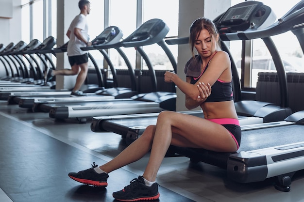 Beautiful sportive girl at gym background filling pain injury concept The girl hurt her arm