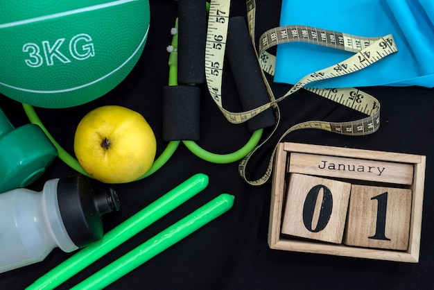 beautiful sports equipment with a wooden clock on January 1 on a spacious black background. The concept of new life